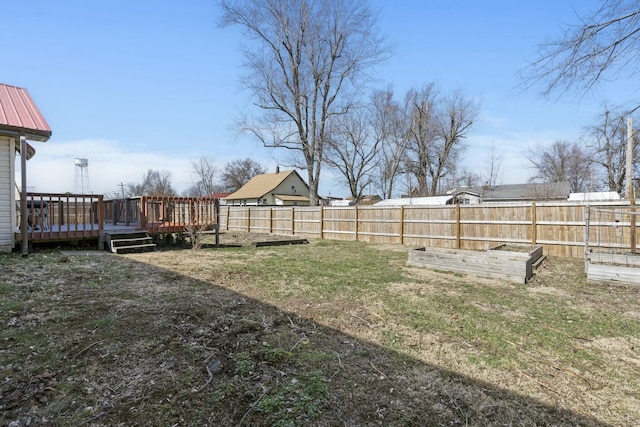 view of yard with a garden, a wooden deck, and fence