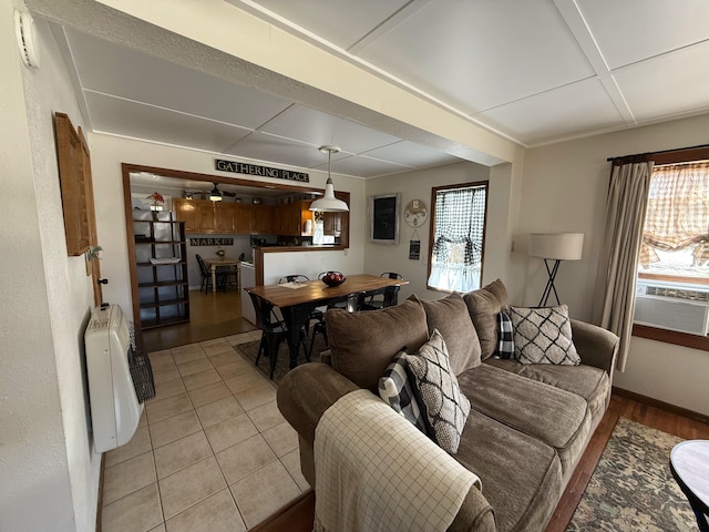 living room with light tile patterned floors, cooling unit, heating unit, and a ceiling fan