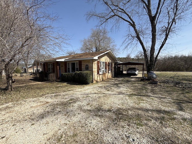 view of property exterior with brick siding, driveway, and a carport