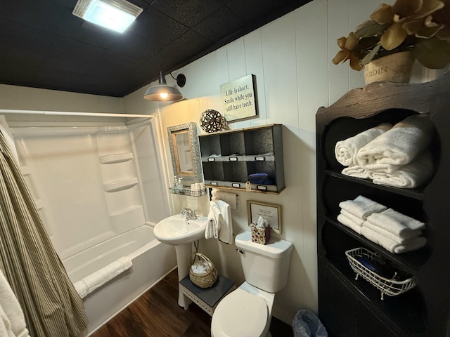 bathroom featuring a sink, toilet, wood finished floors, and shower / bath combination with curtain