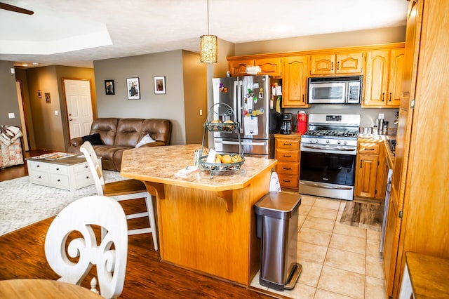 kitchen with a kitchen island, open floor plan, a kitchen bar, light countertops, and stainless steel appliances