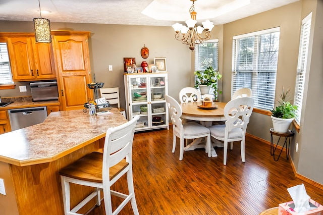 kitchen with a breakfast bar area, dark wood-style floors, light countertops, dishwasher, and a chandelier