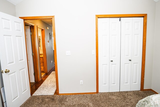 bedroom featuring dark colored carpet, a closet, and baseboards