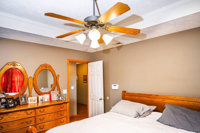 bedroom with ornamental molding, a ceiling fan, visible vents, and a textured ceiling