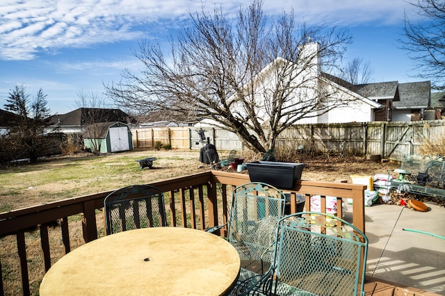 wooden deck with an outbuilding, a fenced backyard, a shed, outdoor dining area, and a patio area