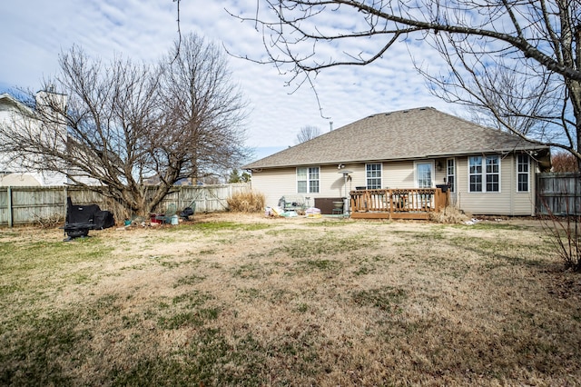 rear view of house with a deck, a lawn, a fenced backyard, and roof with shingles