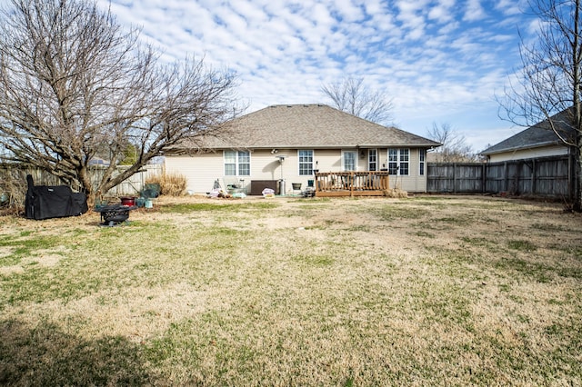 back of house featuring a wooden deck, a lawn, roof with shingles, and a fenced backyard