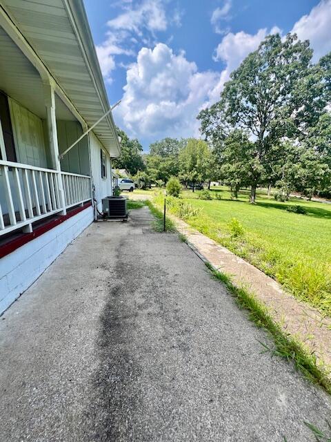 view of side of property with central air condition unit and a lawn