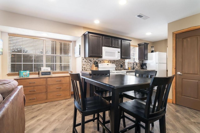 kitchen with white appliances, visible vents, light wood-style flooring, decorative backsplash, and light countertops