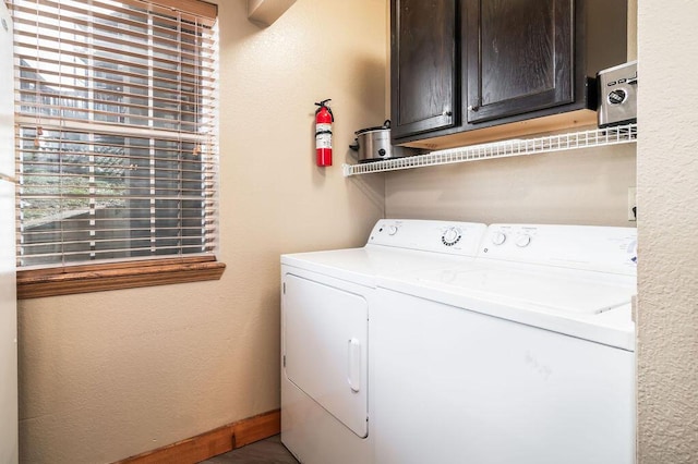 laundry room with washer and clothes dryer, cabinet space, baseboards, and a textured wall