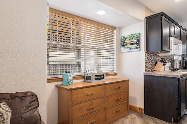 interior space featuring white microwave, baseboards, light wood-style floors, and light countertops