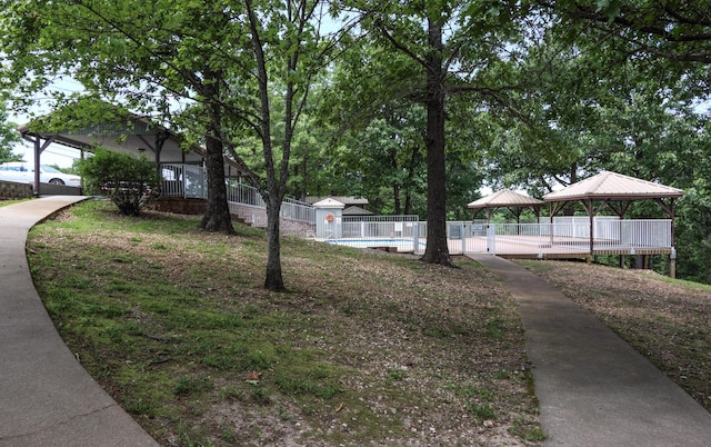 surrounding community with a gazebo, a swimming pool, and fence