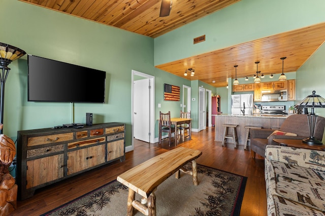 living area with dark wood finished floors, vaulted ceiling, baseboards, and wooden ceiling