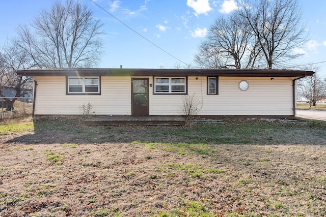 ranch-style home with a wooden deck, a front lawn, and fence