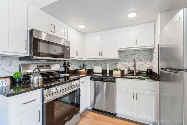 kitchen with a sink, light wood-style floors, appliances with stainless steel finishes, and white cabinets