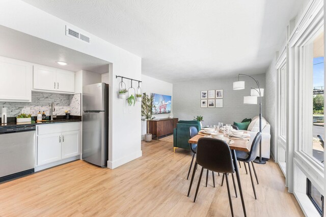 dining room featuring light wood-style flooring, baseboards, and visible vents