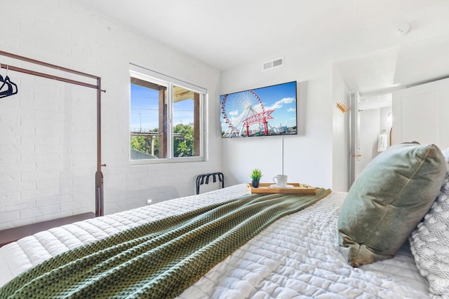 bedroom featuring visible vents and brick wall