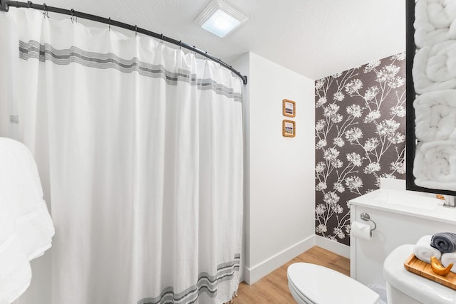 bathroom with curtained shower, baseboards, toilet, wood finished floors, and a sink