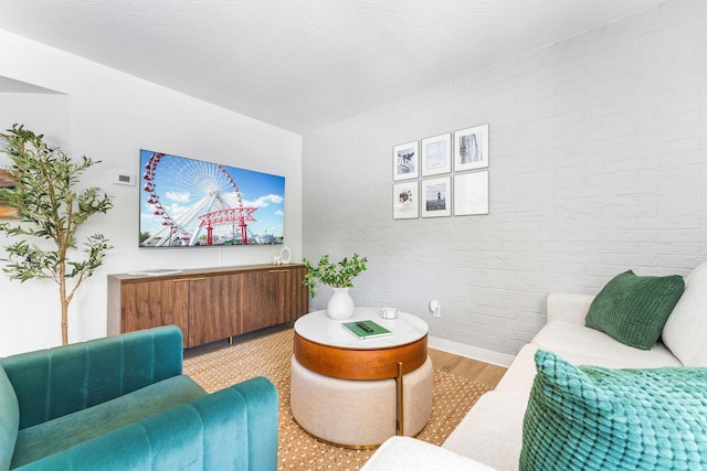 living room featuring light wood-style flooring and brick wall