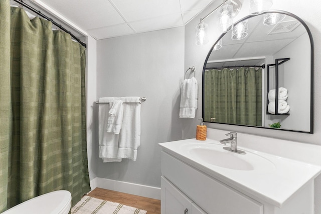 bathroom with vanity, wood finished floors, visible vents, baseboards, and a drop ceiling