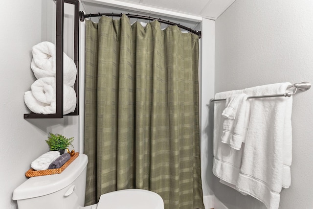 bathroom with curtained shower and toilet