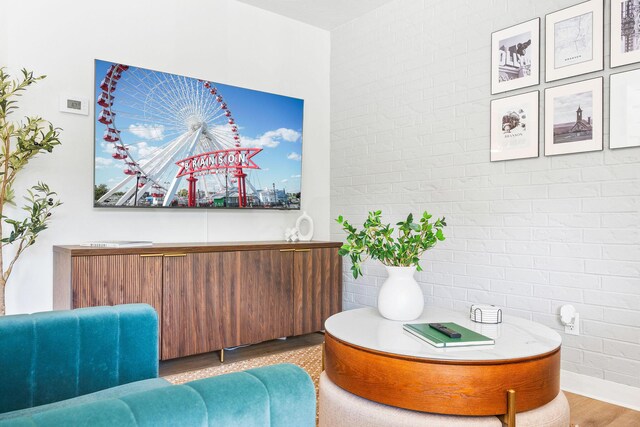 sitting room with wood finished floors, radiator, and brick wall