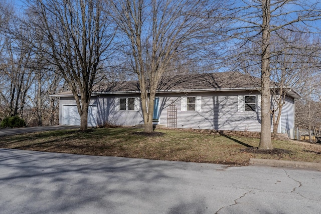 ranch-style house with a front yard, an attached garage, and driveway