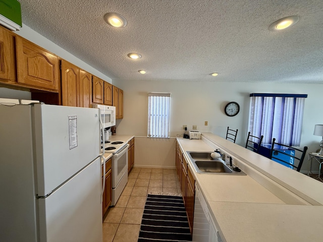 kitchen featuring white appliances, light tile patterned flooring, a sink, light countertops, and brown cabinets