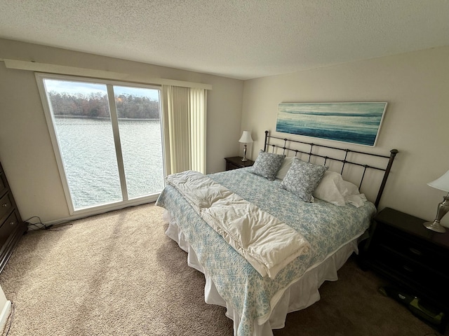 bedroom with a water view, carpet, access to exterior, and a textured ceiling