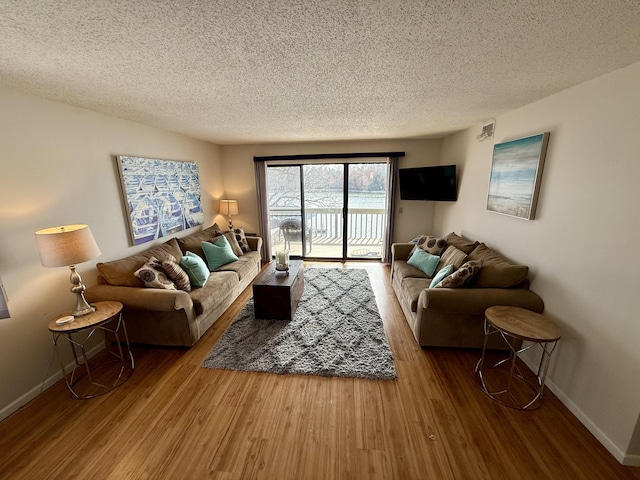 living room featuring baseboards, a textured ceiling, and wood finished floors