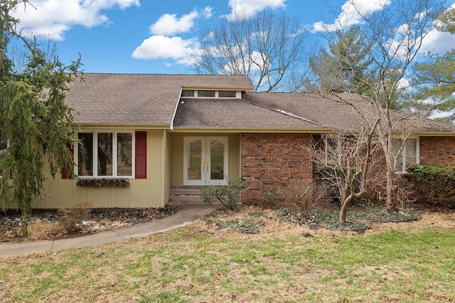 view of front of home featuring french doors, brick siding, and roof with shingles