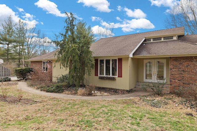 view of property exterior featuring french doors, brick siding, and roof with shingles