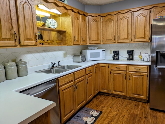 kitchen featuring a sink, light countertops, dark wood finished floors, and stainless steel appliances