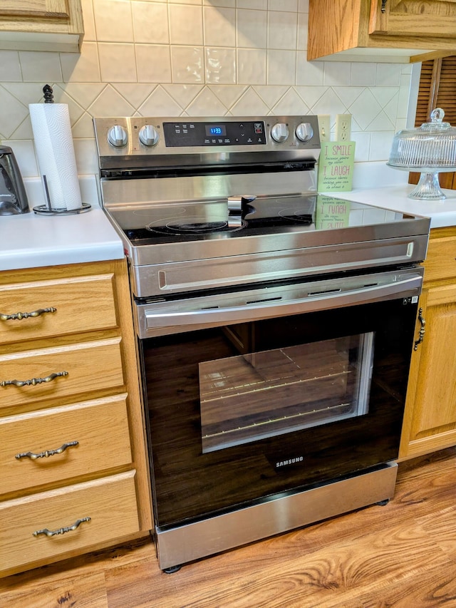 kitchen with backsplash, stainless steel electric range oven, and light countertops