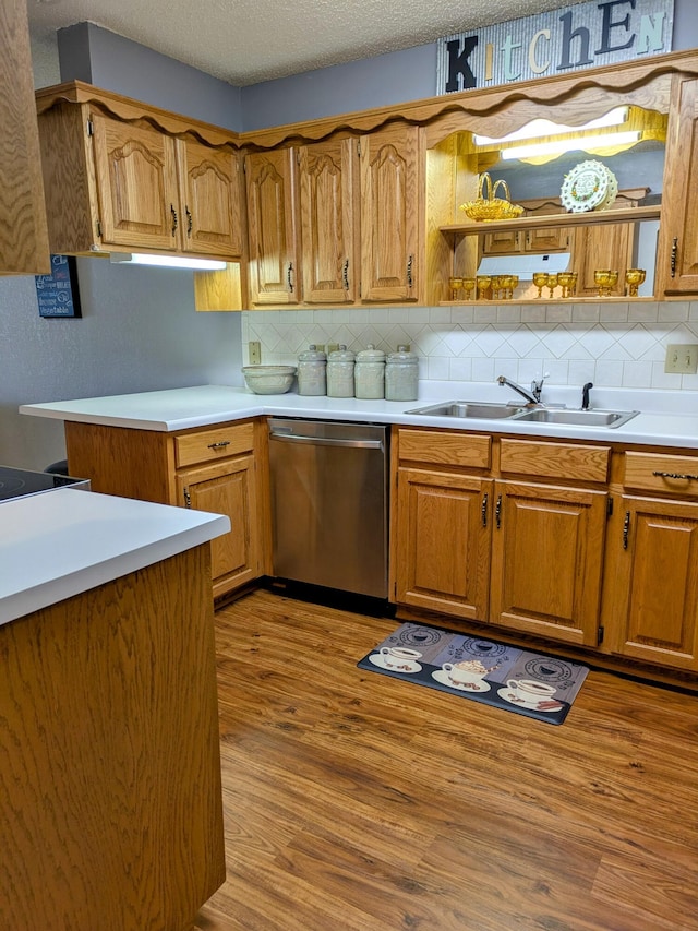 kitchen featuring a sink, stainless steel dishwasher, light wood-style flooring, and a textured ceiling