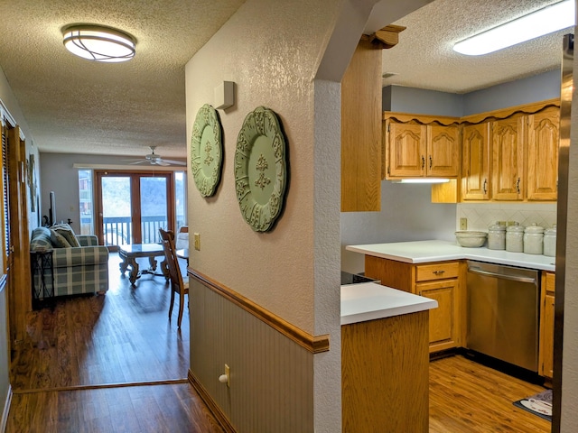 kitchen with a textured ceiling, dark wood-style floors, wainscoting, light countertops, and dishwasher