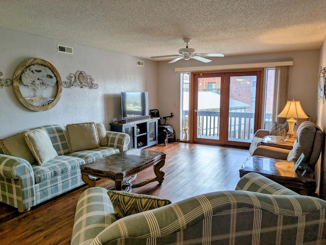 living room with visible vents, a textured ceiling, and wood finished floors