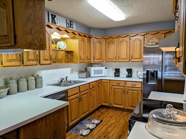 kitchen with a sink, dark wood-style floors, black range with electric cooktop, stainless steel fridge, and white microwave