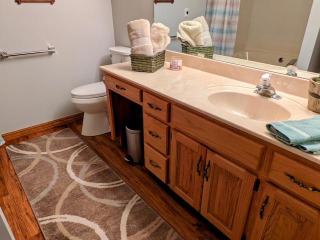 bathroom with vanity, wood finished floors, baseboards, shower / bath combination with curtain, and toilet