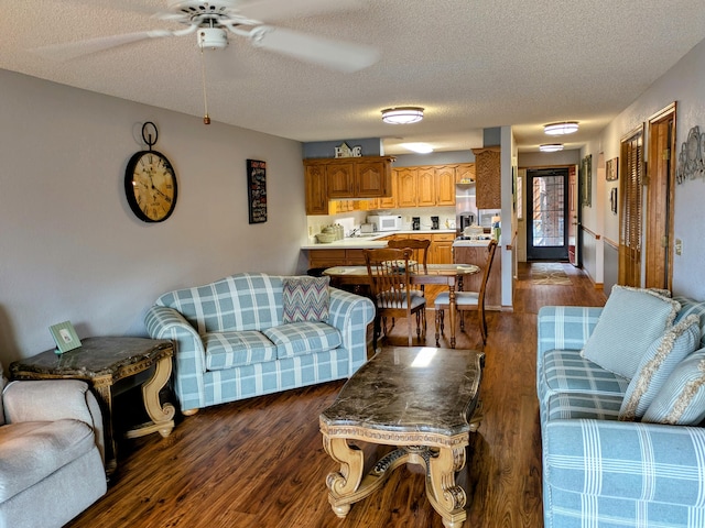 living room with ceiling fan, dark wood-style flooring, and a textured ceiling