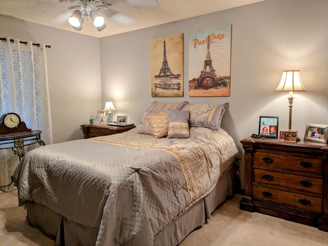 bedroom featuring a ceiling fan, light colored carpet, and a textured ceiling