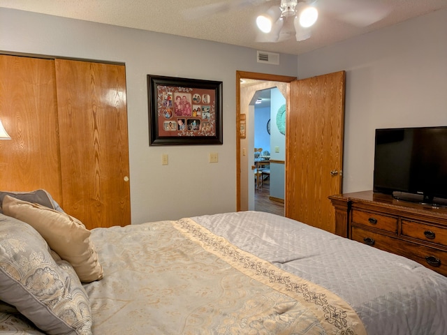 bedroom with a closet, visible vents, a textured ceiling, and a ceiling fan