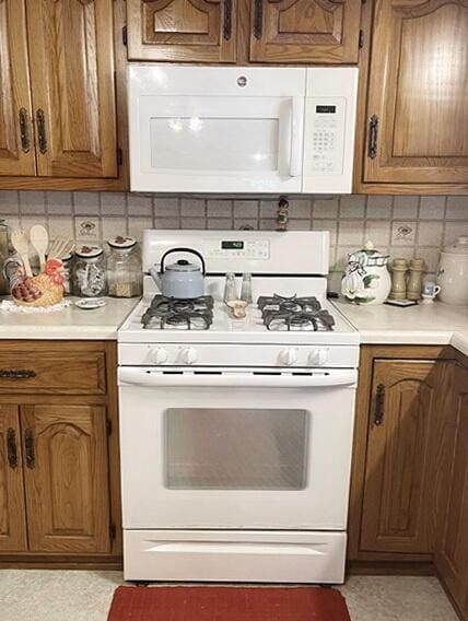 kitchen featuring white appliances, tasteful backsplash, light countertops, and brown cabinets