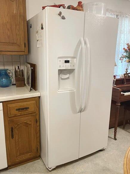 interior space with white appliances, tasteful backsplash, brown cabinetry, and light countertops