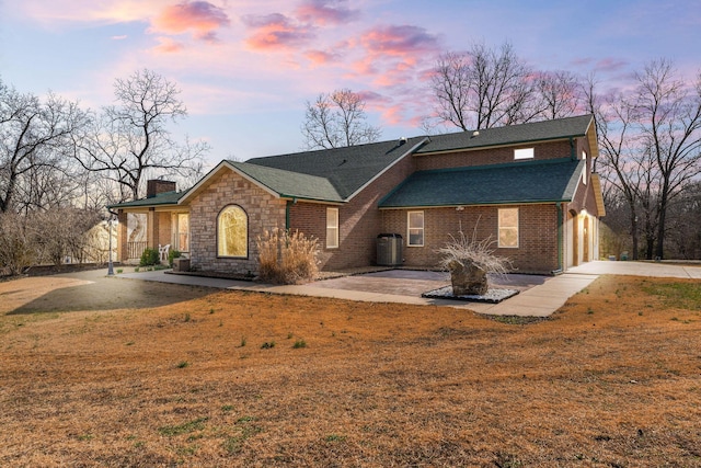 view of front facade with a yard, concrete driveway, a garage, brick siding, and a chimney