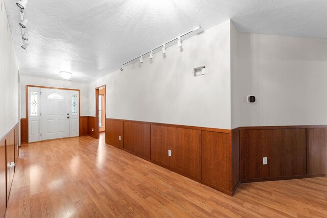 foyer entrance featuring track lighting, light wood-style floors, a wainscoted wall, and a textured ceiling