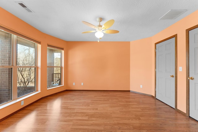 empty room with visible vents, light wood-type flooring, and baseboards