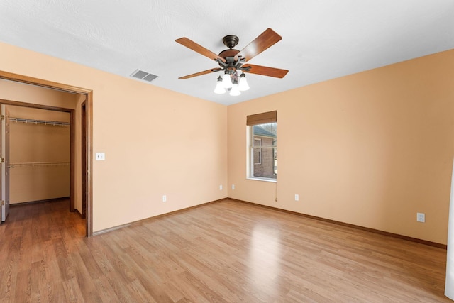 empty room featuring light wood-style flooring, baseboards, visible vents, and ceiling fan