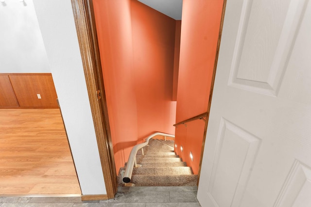 stairway featuring wainscoting, wood walls, and wood finished floors