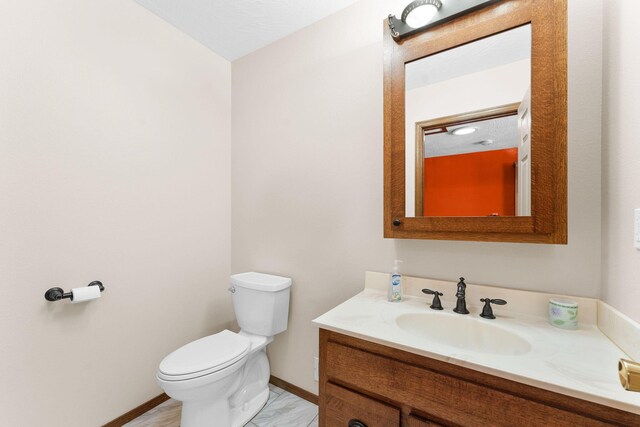 bathroom featuring toilet, vanity, and baseboards